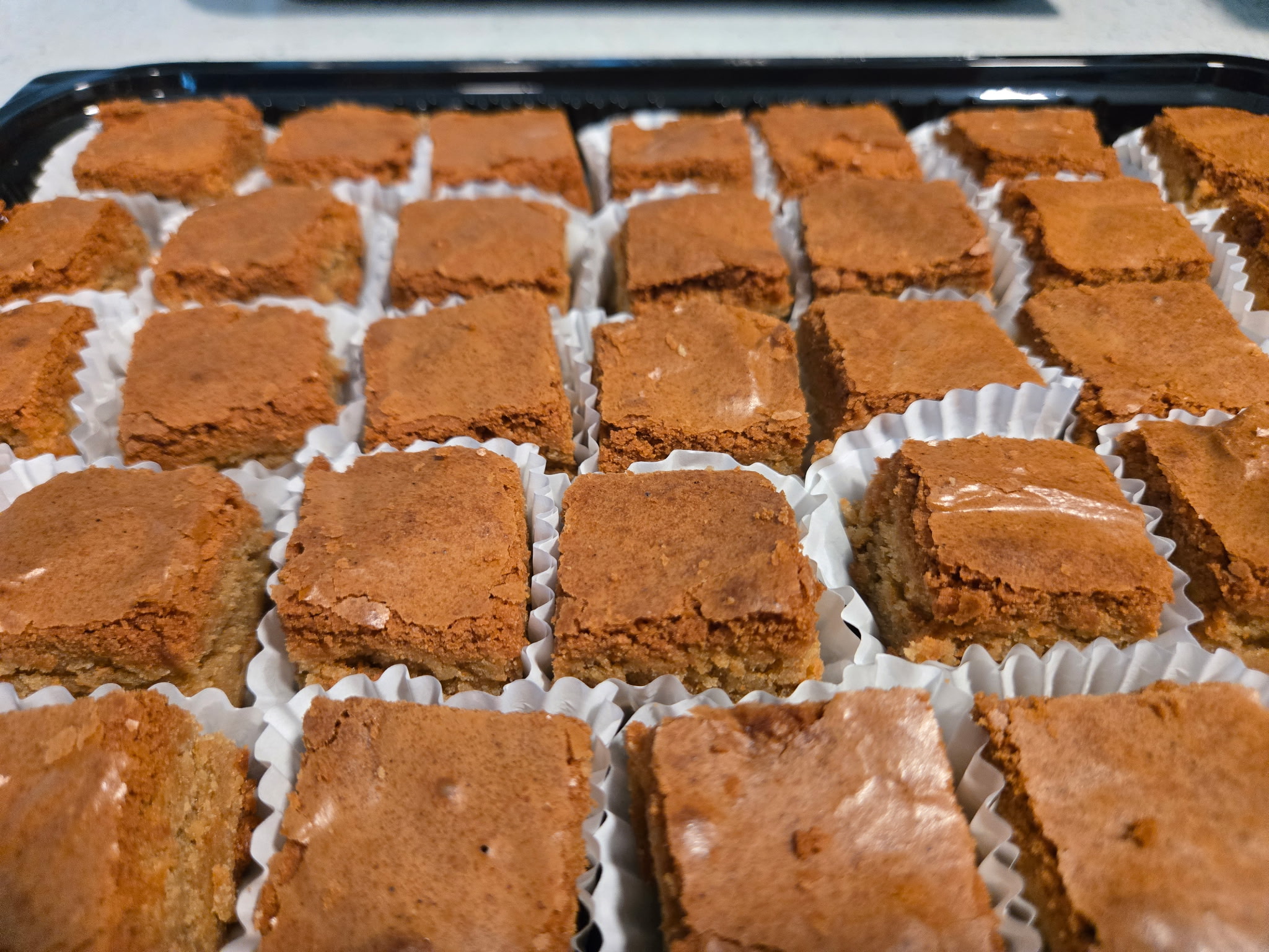 Tray of golden Koko's Kaleidoscope blondies in paper cups