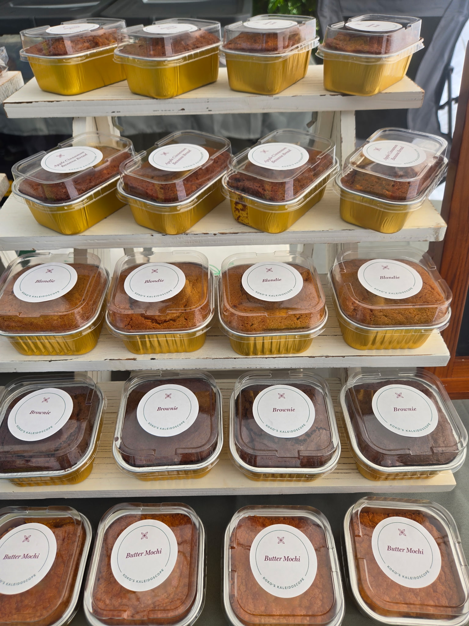 Shelves of Koko's Kaleidoscope banana breads, blondies, brownies and butter mochi in gold-lined packaging
