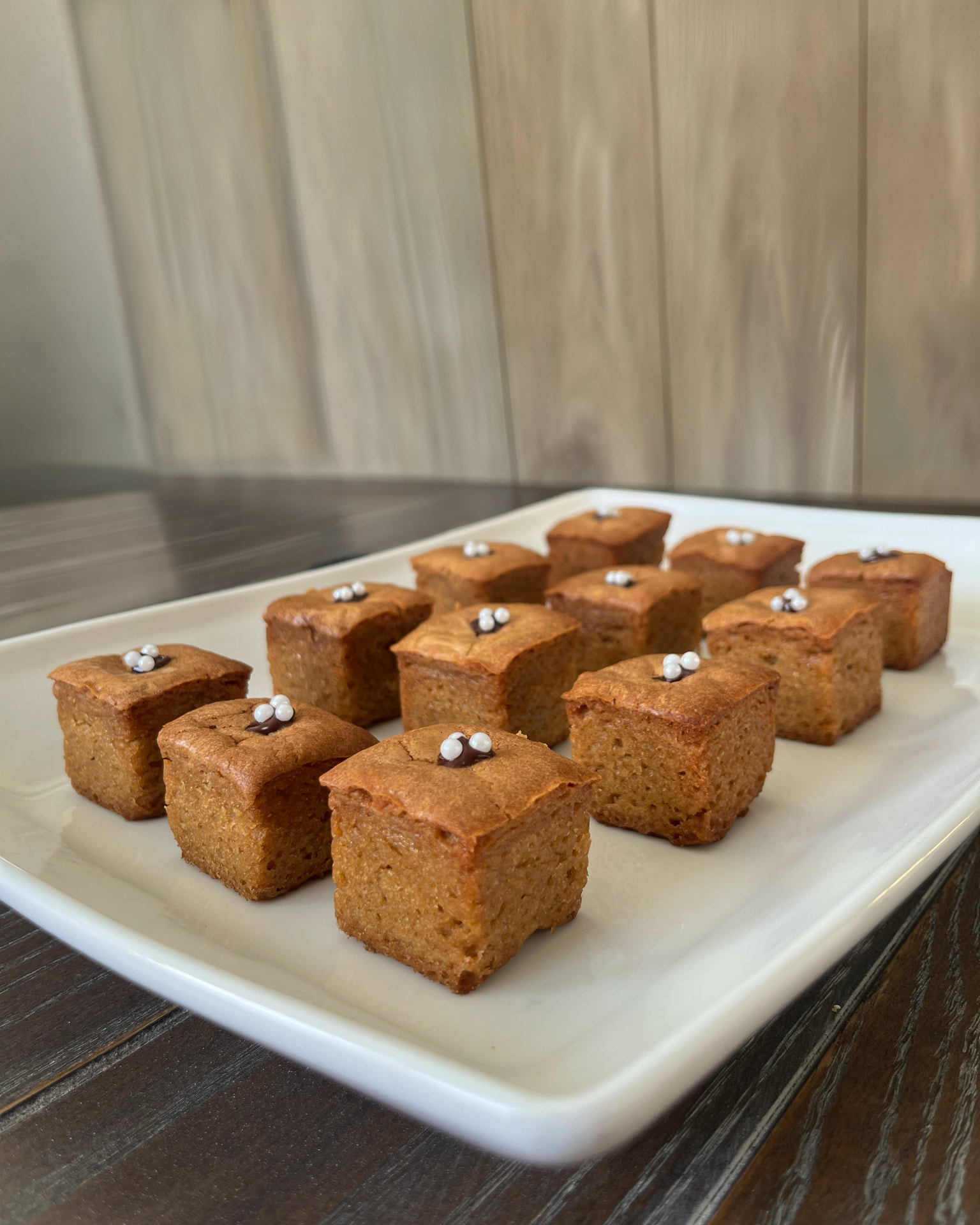 Platter of golden Koko's Kaleidoscope blondie bites topped with chocolate and white sugar pearls