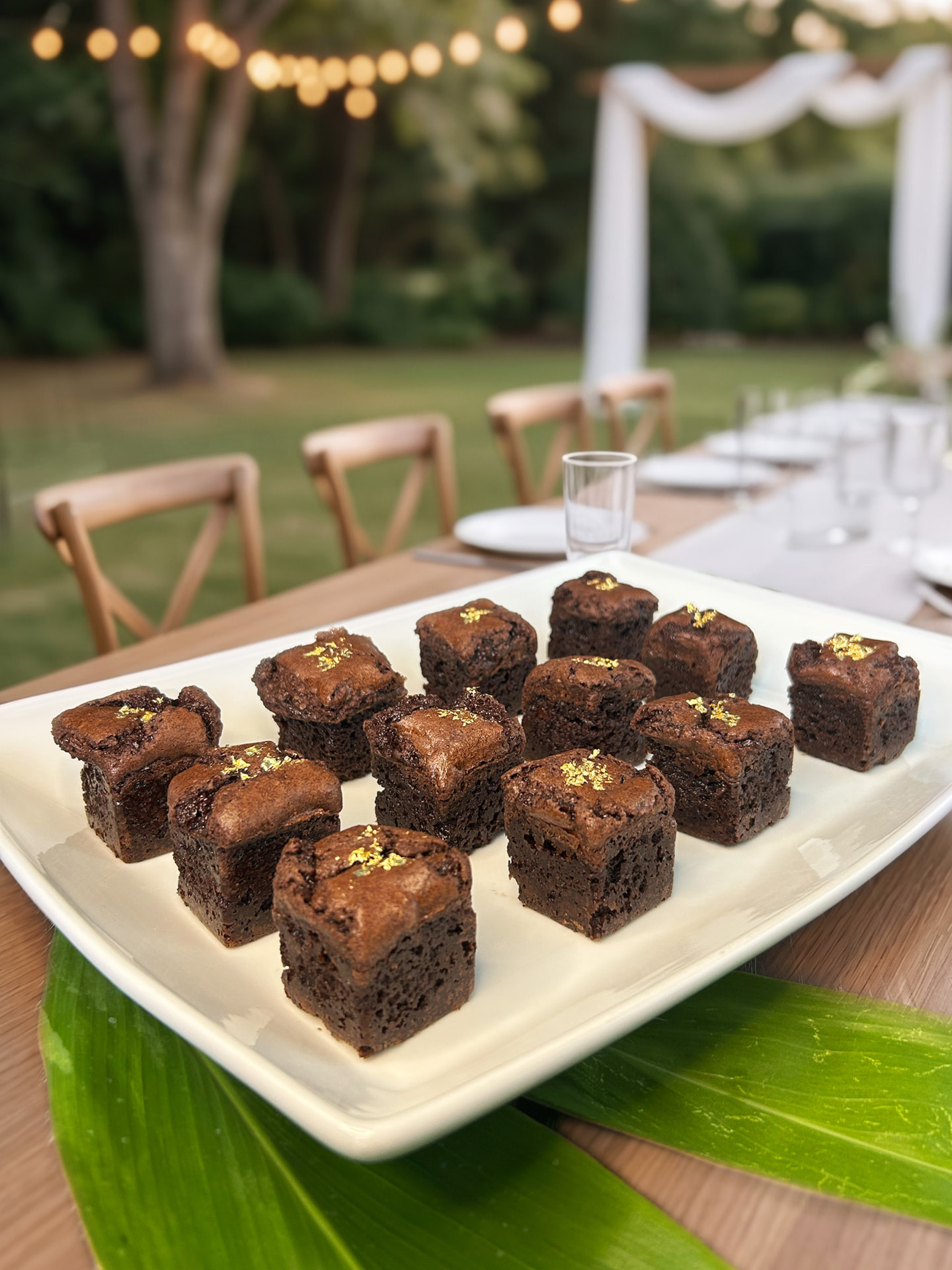 Platter of fudgy Koko's Kaleidoscope brownie bites topped with edible gold leaf at an outdoor Hawaii wedding reception